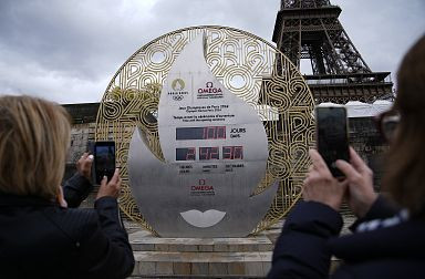 Tourists capture the anticipation of the Paris 2024 Olympics, photographing the official countdown clock in the city center.