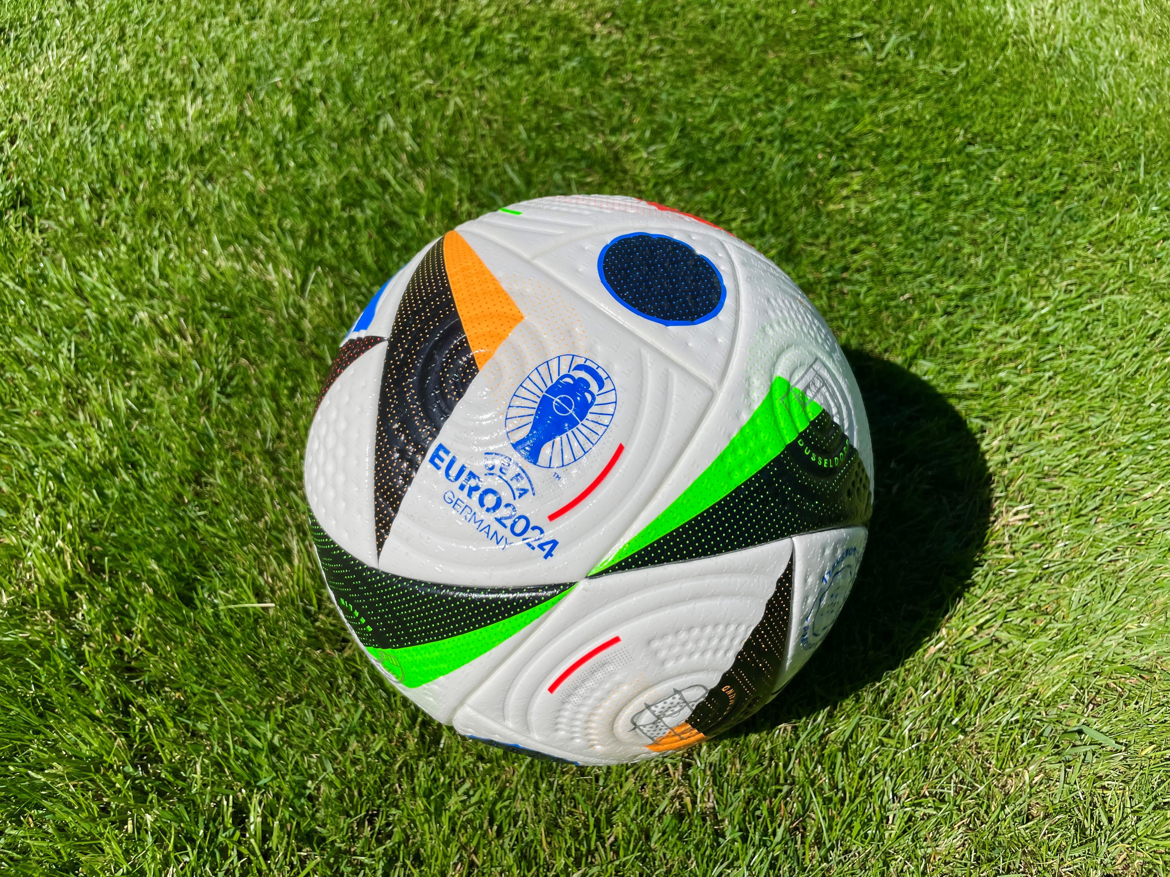 Image of the Adidas Fussballliebe ball on a freshly trimmed lawn.