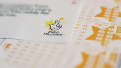 alt text: Close up of stacked EuroMillions lottery tickets.