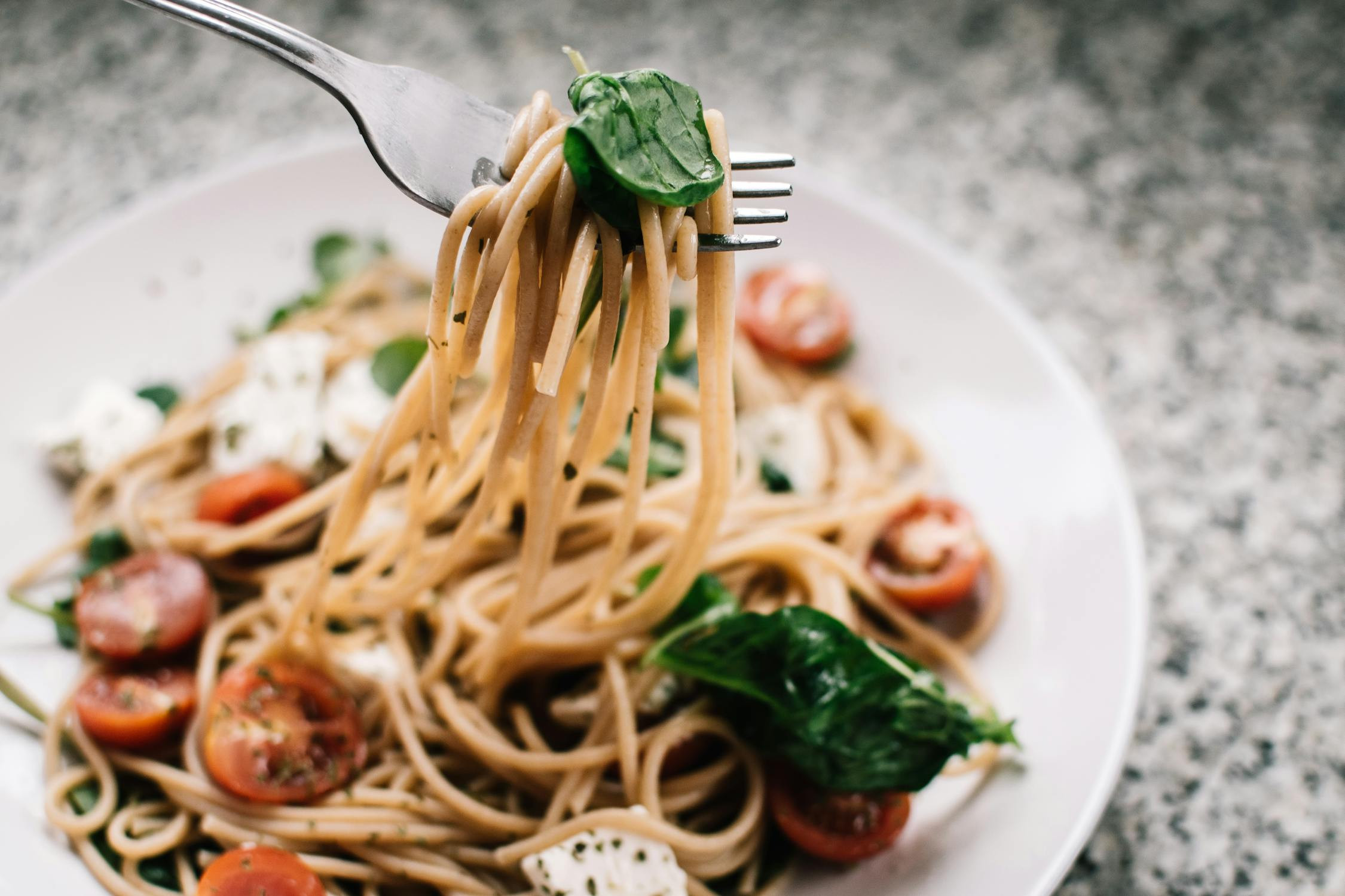 A table setting with a plate of pasta, a glass of wine, and bread, illustrating dining experiences possible with 168 Euros in Europe.